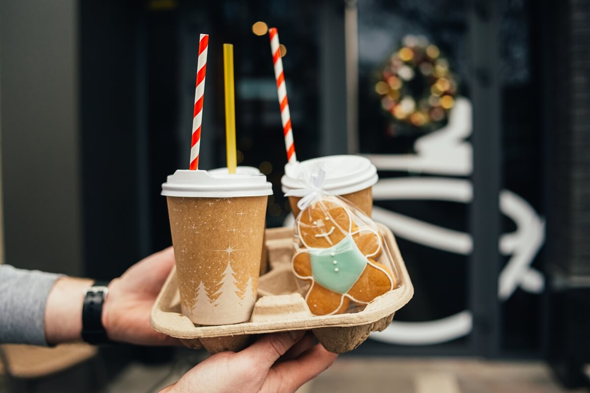 Man holding a pack of Christmas themed custom printed compostable paper cups.