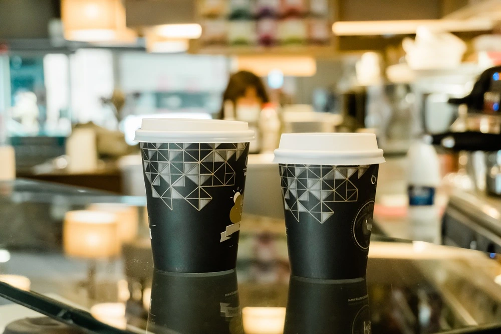 Branded takeaway coffee cups on a café counter, showing how custom cups can help a business get seen.
